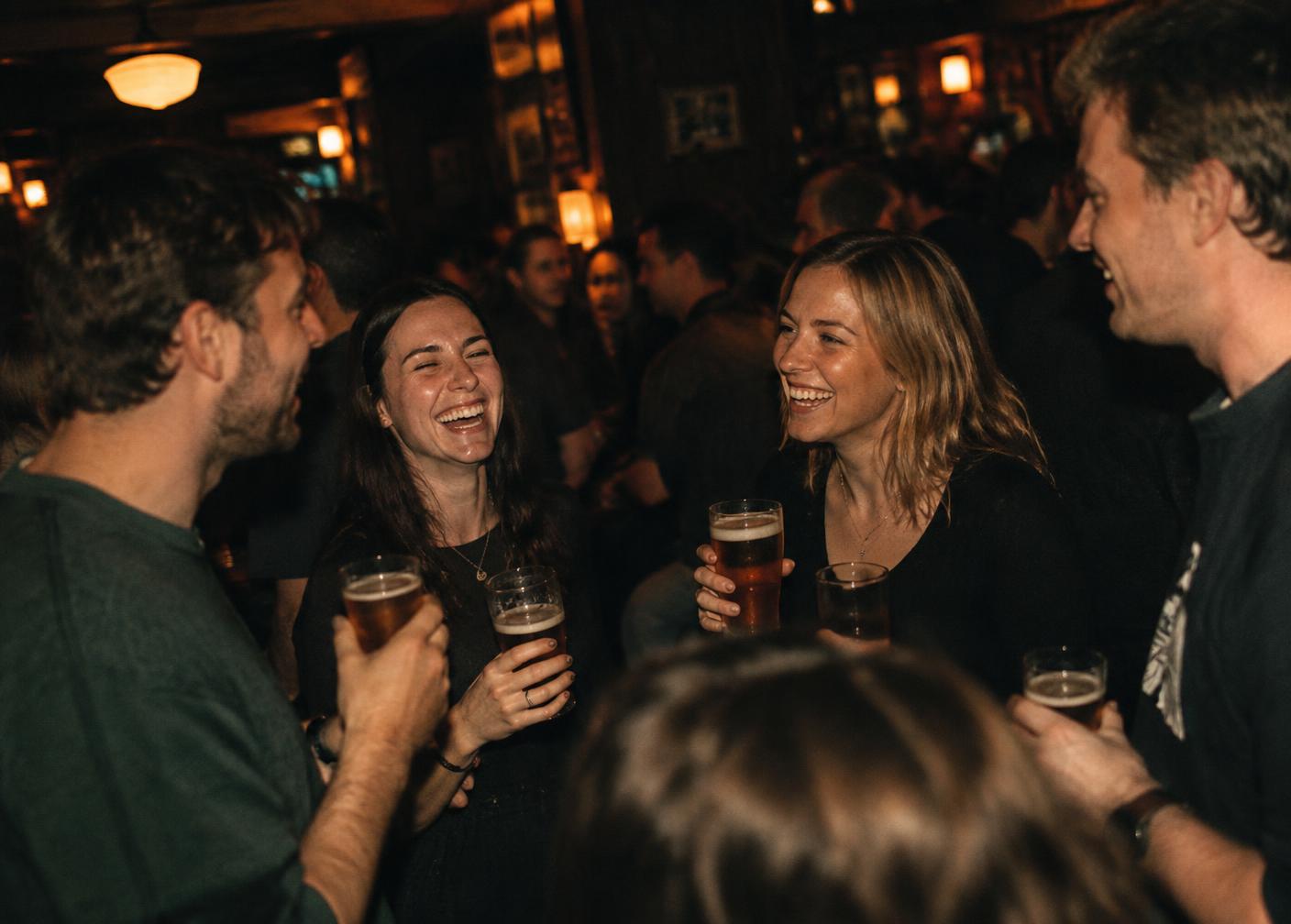 Društvo se smeje uz pivo u punom pubu